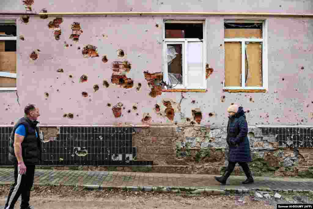 Pleshan greets a neighbor near one of Izyum&#39;s war-scarred residential buildings. Once home to 45,000 residents, the town was liberated by Ukrainian soldiers in September after being occupied by Russian forces. &nbsp;