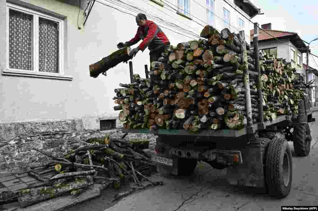 Un bărbat descarcă lemne de foc dintr-un camion în fața unei case din Teteven, Bulgaria, pe 8 decembrie. În Bulgaria, în august anul trecut, a fost impusă o interdicție privind exportul de lemn către țările din afara UE ca răspuns la dublarea prețului lemnului de foc în decurs de un an, în fața masivei cereri. &nbsp;