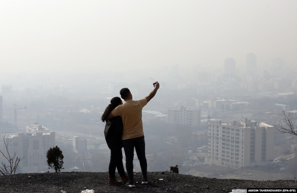 Iranski par snima selfi dok smog zaklanja horizont u Teheranu.