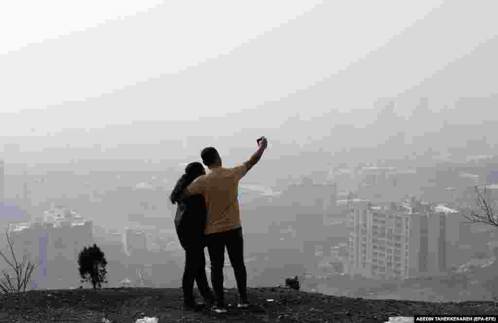 An Iranian couple takes a selfie as smog obscures the skyline in Tehran.&nbsp;
