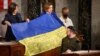 Ukrainian President Volodymyr Zelenskiy gives a Ukrainian national flag to U.S. House Speaker Nancy Pelosi and Vice President Kamala Harris (left) during his address the U.S. Congress at the U.S. Capitol in Washington, D.C. on December 21. 