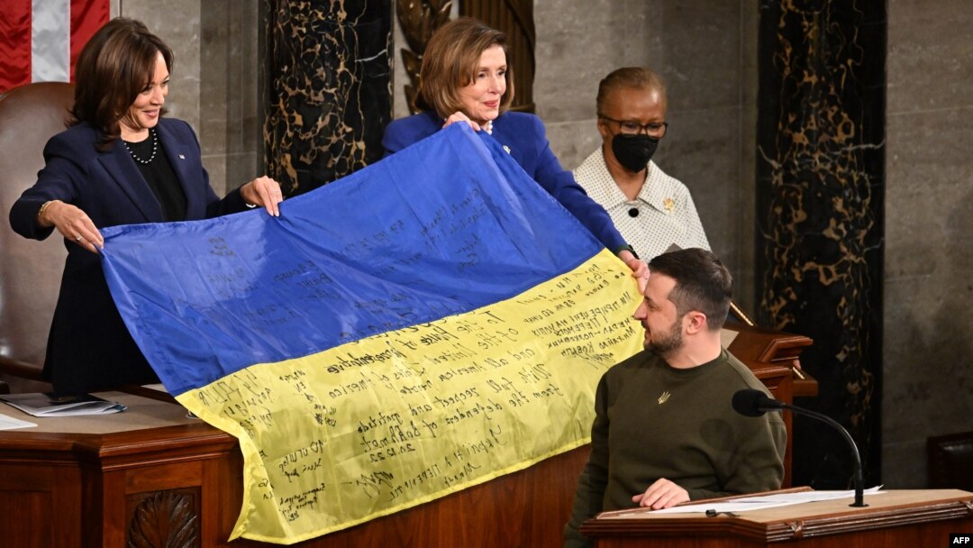Ukrainian President Volodymyr Zelenskiy gives a Ukrainian national flag to U.S. House Speaker Nancy Pelosi and Vice President Kamala Harris (left) during his address the U.S. Congress at the U.S. Capitol in Washington, D.C. on December 21.