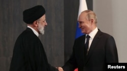 Vlagyimir Putyin orosz elnök kezet fog Ebrahim Raiszi iráni elnökkel a Sanghaji Együttműködési Szervezet (SCO) csúcstalálkozójának margóján tartott találkozón az üzbegisztáni Szamarkandban 2022. szeptember 15-én