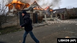 Një banor vendas kalon pranë një shtëpie të goditur nga bombardimet ruse në Herson të Ukrainës, në prag të Krishtlindjeve Ortodokse. 6 janar 2023. 