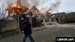 A local resident runs past a burning house hit by Russian shelling in Kherson, Ukraine, on January 6. 