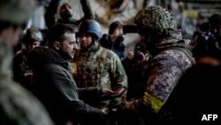 Ukrainian President Volodymyr Zelenskiy (left) hands out a state award to one of his country's soldiers who is defending the eastern frontline city of Bakhmut on December 20. 