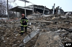A Ukrainian emergency worker walks amid the rubble of a destroyed building following Russian strikes on Kharkiv on December 16.