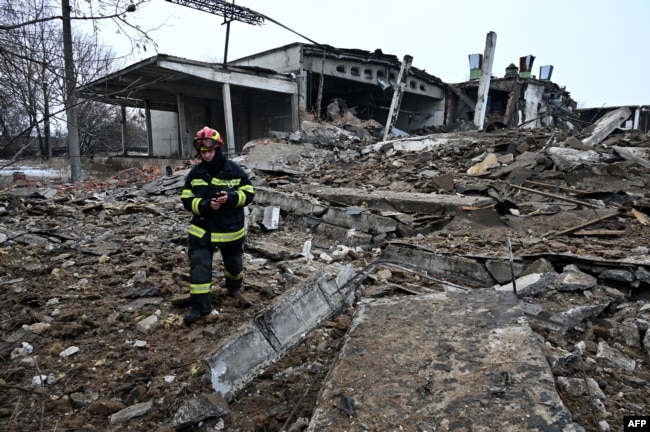 A Ukrainian emergency worker walks amid the rubble of a destroyed building following Russian strikes on Kharkiv on December 16.