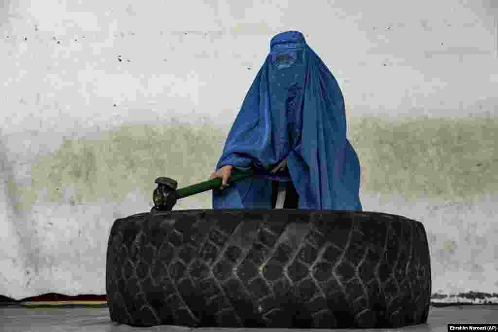 An Afghan woman who practices jiujitsu, a Japanese martial art, poses in Kabul with a sledgehammer she uses for strength exercises. The Taliban authorities have repeatedly promised to allow girls in seventh grade and up to return to school but have not honored their promises.