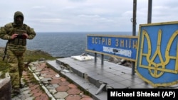 A Ukrainian soldier walks past a sign reading "Snake Island, ours" on Snake Island in the Black Sea on December 18, 2022. 