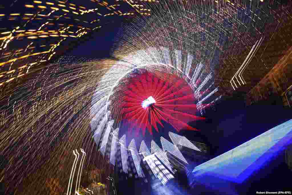 A Ferris wheel and decorative Christmas lights, taken with a low shutter speed and zoomed out, are seen at the Christmas market in downtown Bucharest.