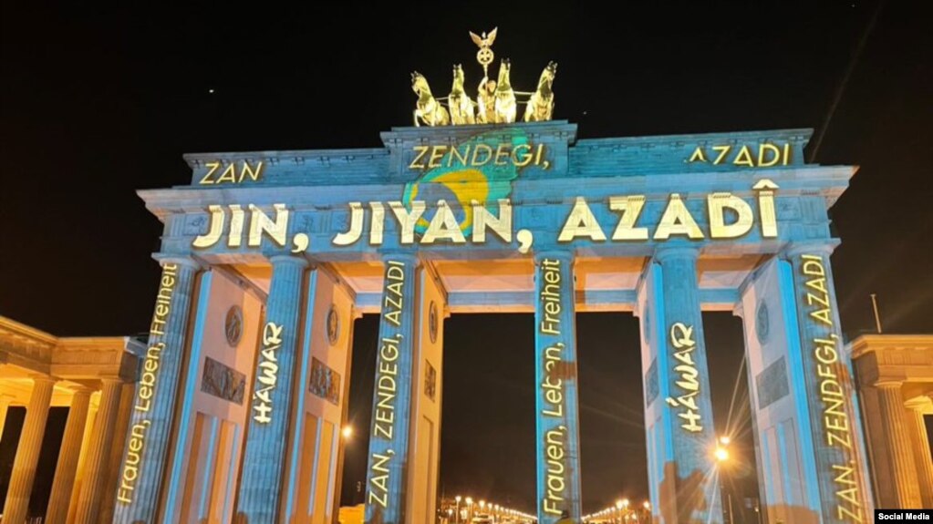 نورپردازی شعار «زن زندگی آزادی» بر دروازۀ براندنبورگ در برلین، آذر ۱۴۰۱