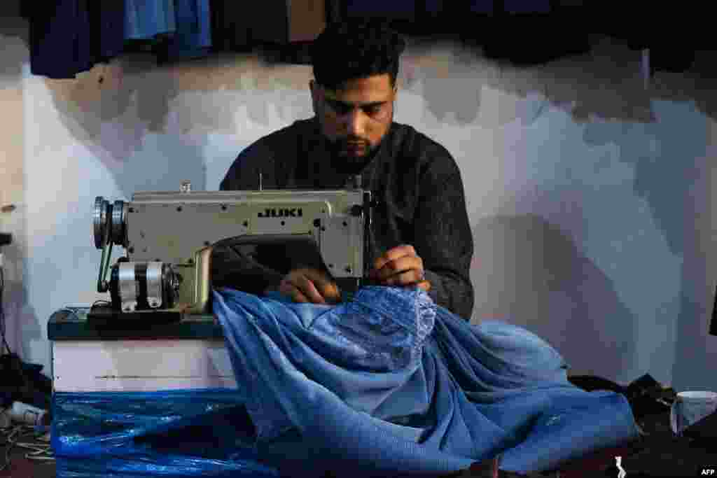 Un croitor afgan coase o burqa în atelierul său din Jalalabad...