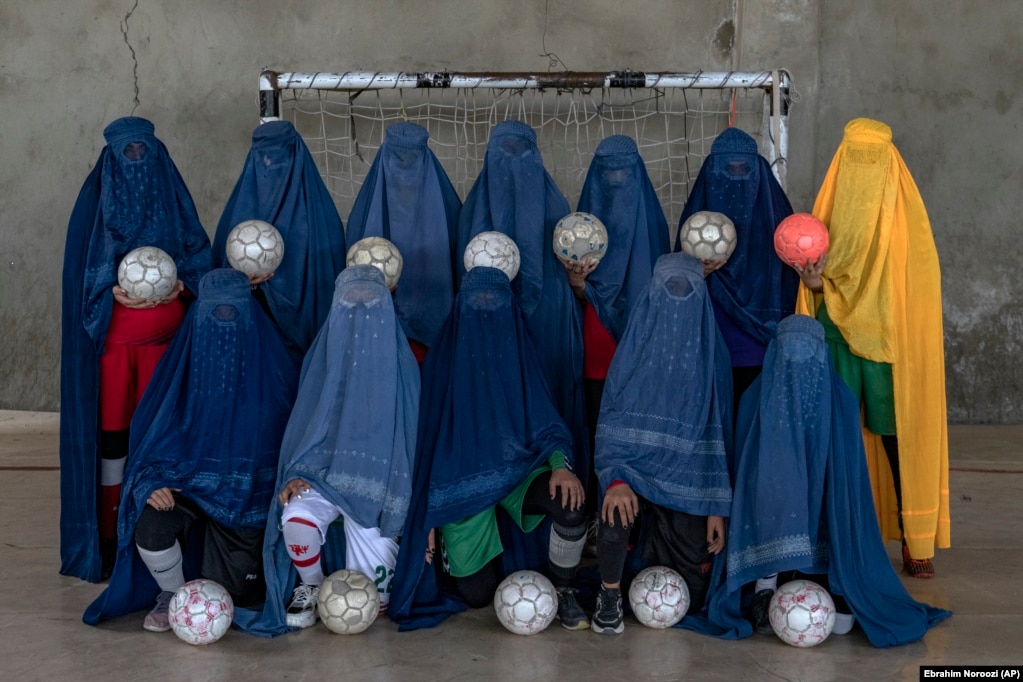 Një ekip afgan i futbollit të grave duke pozuar për një portret në Kabul. Gratë dhe vajzat duhet të fshehin identitetet e tyre me burka – veshje që tërësisht mbulon trupin dhe fytyrën, duke lënë vetëm një hapësirë të rrjetëzuar për të shikuar – teksa ato përballen me frikësime, kërcënime dhe, në disa raste, me rrahje nga vetë familjarët e tyre për shkak se merren me sporte.