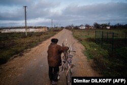 Volodimir Kovalov (77 de ani) cară vreascuri cu bicicleta sa, în satul Posad-Pokrovs'ke, regiunea Herson, 26 decembrie 2022.