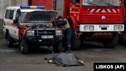 Echipa de intervenții lângă trupul neînsuflețit al unui pompier ucis de bombardamentul rusesc asupra stației de pompieri din Herson, Ucraina, în ajunul Crăciunului ortodox, 6 ianuarie 2023