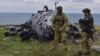 Українські військові стоять на фоні пошкодженого російського військового гелікоптера на острові Зміїний, у Чорному морі, 18 грудня 2022 року, ілюстративне фото