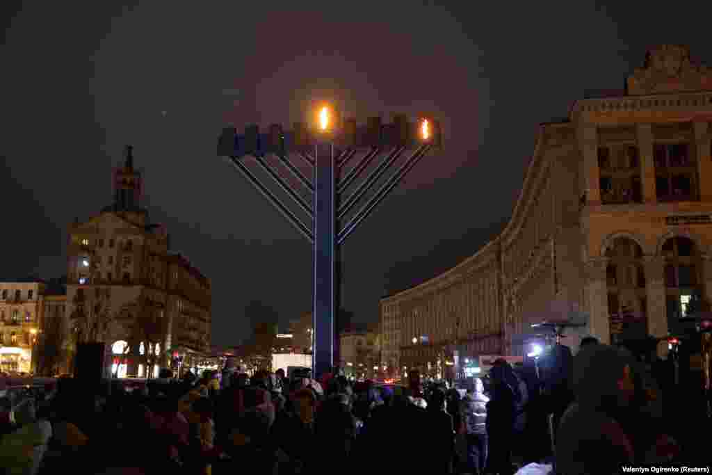 People stand next to a giant menorah during a ceremony for the Jewish festival of Hanukkah at the Independence Square in Kyiv, Ukraine December 18, 2022.