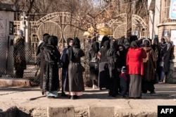 Female university students stopped by the Taliban stand near a university in Kabul in December.