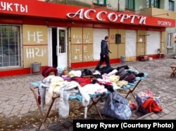 Utcai árusok Mariupolban a háttérben a „Ne gyújtsd fel, lakóház” felirattal. A szerző, Szergej Riszev engedélyével