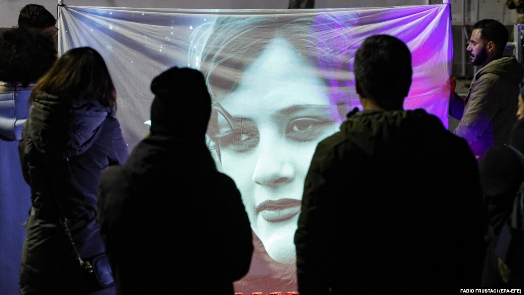 Protesters looks at an image of Mahsa Amini, whose death in police custody in September has sparked months of protests, during a candlelight vigil in front of Iranian Embassy in Rome.