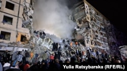 Rescuers, relatives, and residents crowd around an apartment building heavily damaged by a Russian missile strike in Dnipro, Ukraine, on January 14.