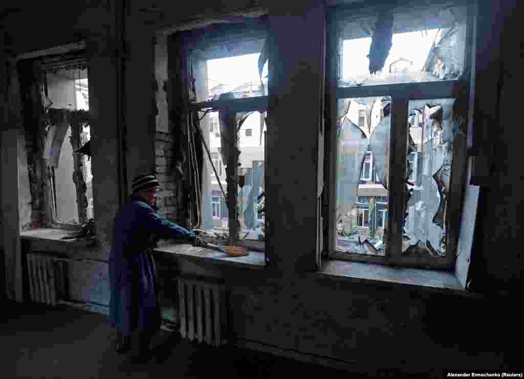 O femeie mătură geamurile sparte la un spital avariat de bombardamentele recente din Donețk, Ucraina.