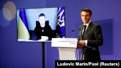 Ukrainian President Volodymyr Zelensky listens via video link as French President Emmanuel Macron delivers a speech during a French-Ukrainian conference for resilience and reconstruction in Paris on December 13.