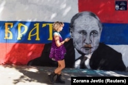 Жінка йде біля фрески із зображенням президента Росії Володимира Путіна зі словом «Брат», яку спаплюжили червоною фарбою після повномасштабного вторгнення Росії в Україну, у Белграді, Сербія
