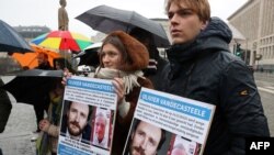 Демонстранти држат фотографии од белгискиот хуманитарен работник Оливие Вандекастиле за време на демонстрациите во Брисел на 25 декември 2022 година