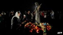  O femeie depune flori în timpul unui eveniment de comemorare a victimelor foametei din Ucraina - Holodomor - la Kiev, pe 26 noiembrie 2022.