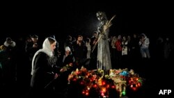 Жена полага цветя на паметника на жертвите на Гладомора в Киев по време на отбелязването на 90-ата годишнина. 26 ноември, 2022