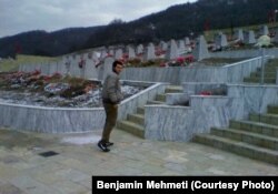Benjamin Mehmeti në varrezat e Reçakut, ku janë varrosur motra e madhe dhe babai i tij - të vrarë gjatë Masakrës së Reçakut.