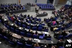 Канцлер Германии Олаф Шольц (на трибуне) обращается к делегатам во время заседания Бундестага (нижней палаты парламента). Берлин, 23 ноября 2022 года