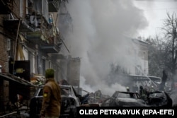 Пожарные работают на месте разрушенного в результате российского обстрела многоквартирного дома в Вышгороде, недалеко от Киева, 23 ноября 2022 года
