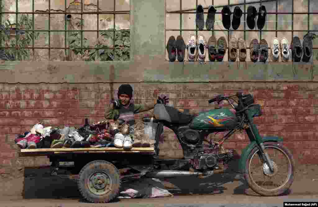 A Pakistani boy selling secondhand shoes waits for customers in Peshawar.
