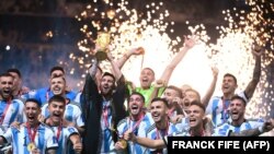 Fudbalska reprezentacija Argentine slavi pobedu na Svetskom prvenstvu u fudbalu nakon dodele pehara koji drži Lionel Mesi, Doha, 18. decembar