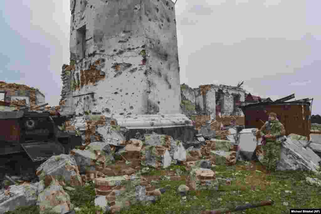 Un soldat ucrainean stă la baza unui far deteriorat, vechi de 180 de ani, de pe Insula Șerpilor. Fotografii din 2009 arată o clădire din jurul acestui far care a fost distrusă în timpul luptei pentru insulă.
