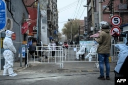 Охранники в средствах индивидуальной защиты (СИЗ) в жилом комплексе, заблокированном из-за ограничений, связанных с коронавирусом Covid-19. Пекин, 24 ноября 2022 года