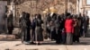 Studentice stoje ispred ograde i naoružanog osoblja pored univerziteta u Kabulu 21. decembra 2022.
