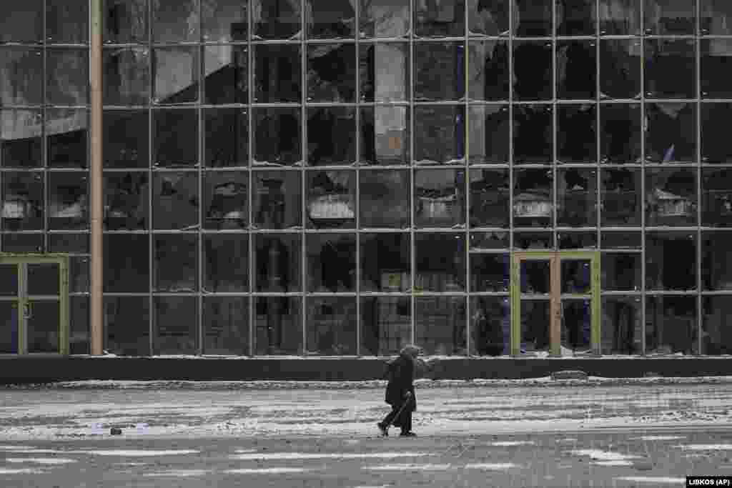 Një banore duke ecur pranë një ndërtese të shkatërruar në Bahmut.