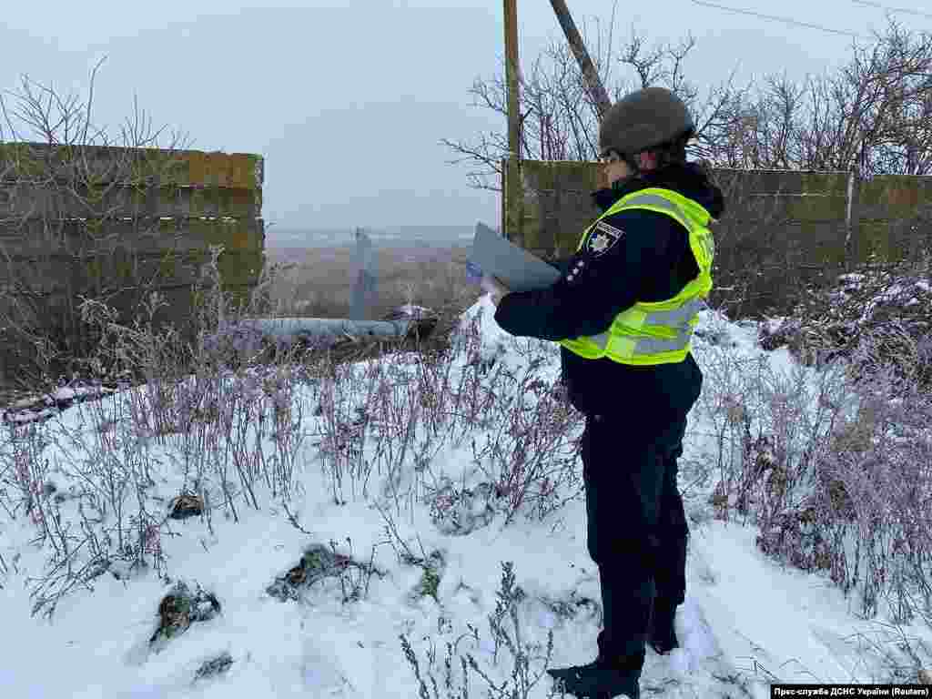 Поліцейський стоїть біля частини російської крилатої ракети, збитої українськими силами ППО під час атаки Росії на Україну, Київська область, 16 грудня 2022 року
