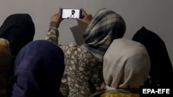 Afghan women watch the speech of the Taliban's minister for higher education, who banned women from university education in December.