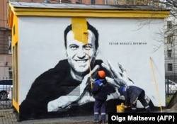 Një punëtor duke mbuluar me ngjyrë mbishkrimet për Navalnyn në Shën Petersburg, në prill të vitit 2021. Pranë portretit të Navalnyt shkruan "Heroi i kohëve të reja".