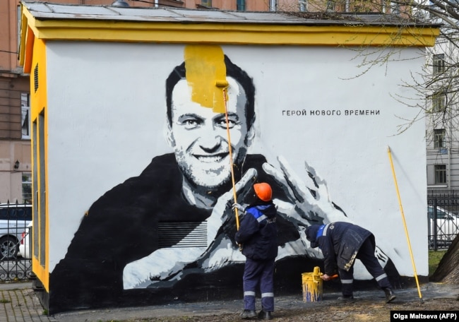 Një punëtor duke mbuluar me ngjyrë mbishkrimet për Navalnyn në Shën Petersburg, në prill të vitit 2021. Pranë portretit të Navalnyt shkruan "Heroi i kohëve të reja".