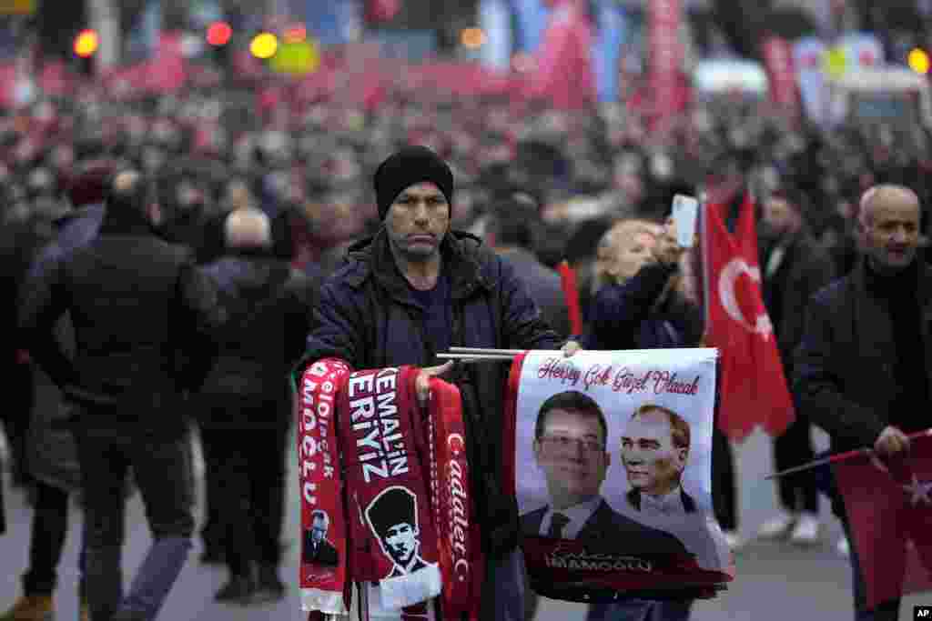 Уличен търговец продава знамена и картички със снимката на кмета на Истанбул Екрем Имамоглу по време на митинг пред сградата на общината в Истанбул, четвъртък, 15 декември 2022 г.