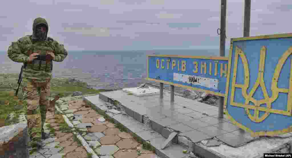 Un soldat ucrainean este surprins lângă un semn pe care scrie &bdquo;Insula Șerpilor&rdquo;, iar dedesubt un graffiti cu mesajul &bdquo;A noastră!&rdquo; Insula Șerpilor a fost capturată de navele de război rusești pe 24 februarie, în primele ore ale invaziei din Ucraina.