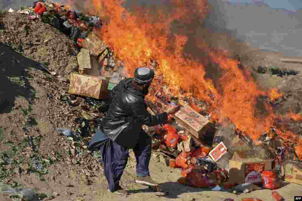 A local government official burns expired food items removed from shops on the outskirts of Kandahar.
