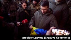 Президент Украины Владимир Зеленский во время визита в Бахмут с украинским флагом с надписями, который ему передали защитники города. Бахмут, Донетчина, 20 декабря 2022 года