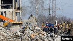 Спасителни екипи разчистват останките от разрушеното училище, част от комплекс от сгради от съветско време